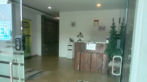 A reception area with a wooden desk, a potted plant, and a sign on the wall. - Le Deon Hotel (Batu Gajah)