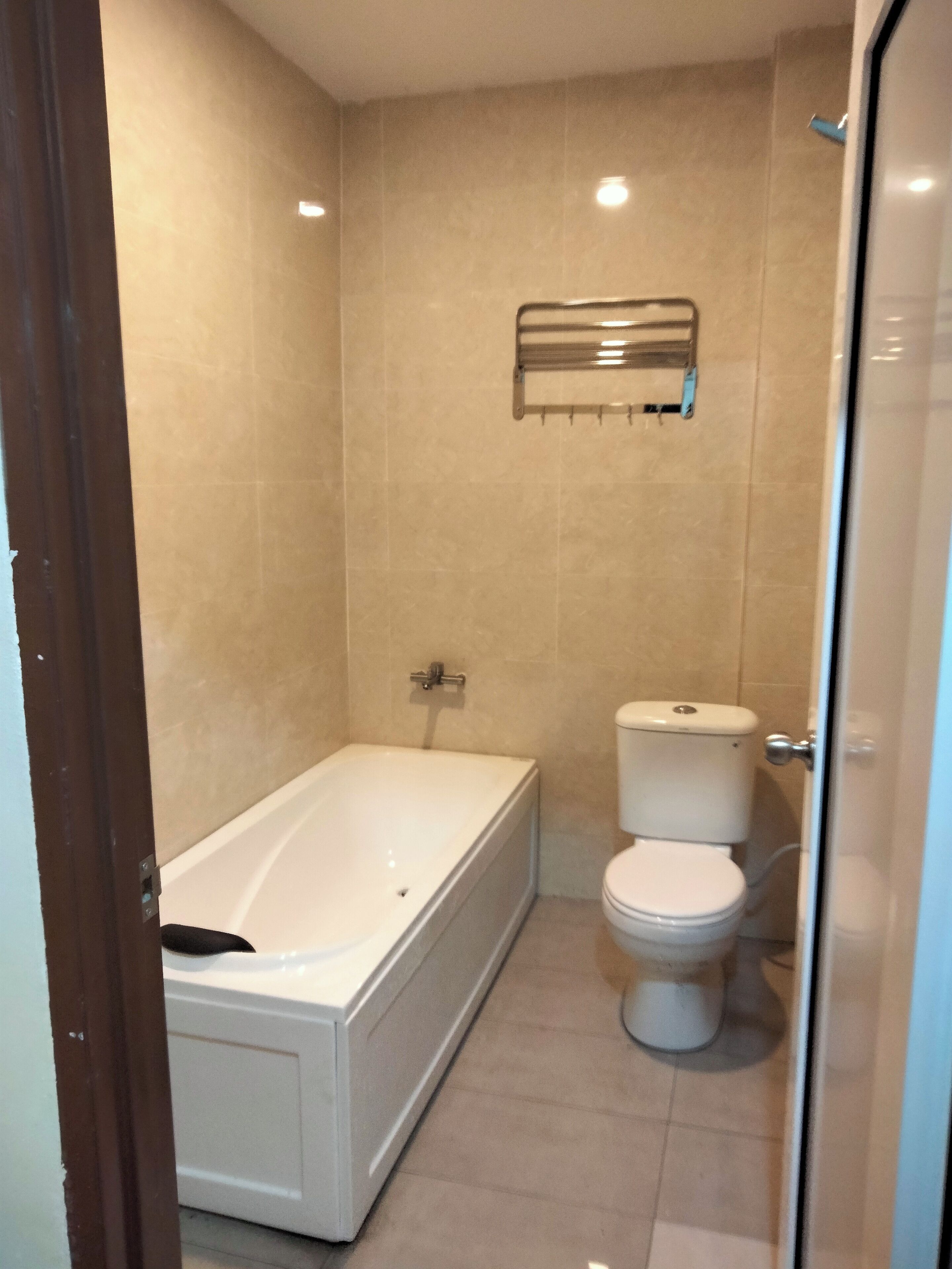 Un baño con bañera, inodoro y perchero para toallas.