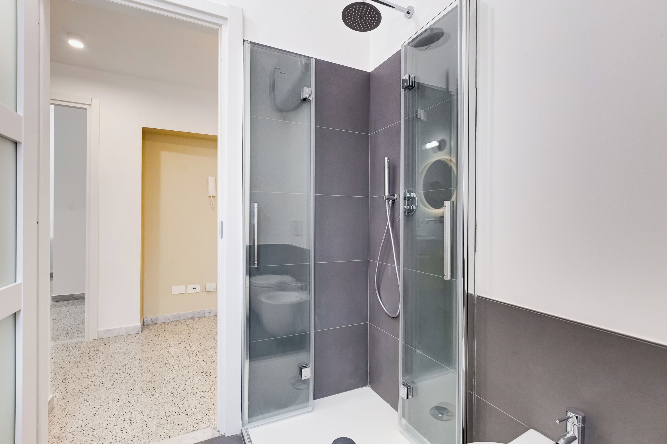 Ein modernes Badezimmer mit einer Duschkabine, einer Toilette und einem Waschbecken.