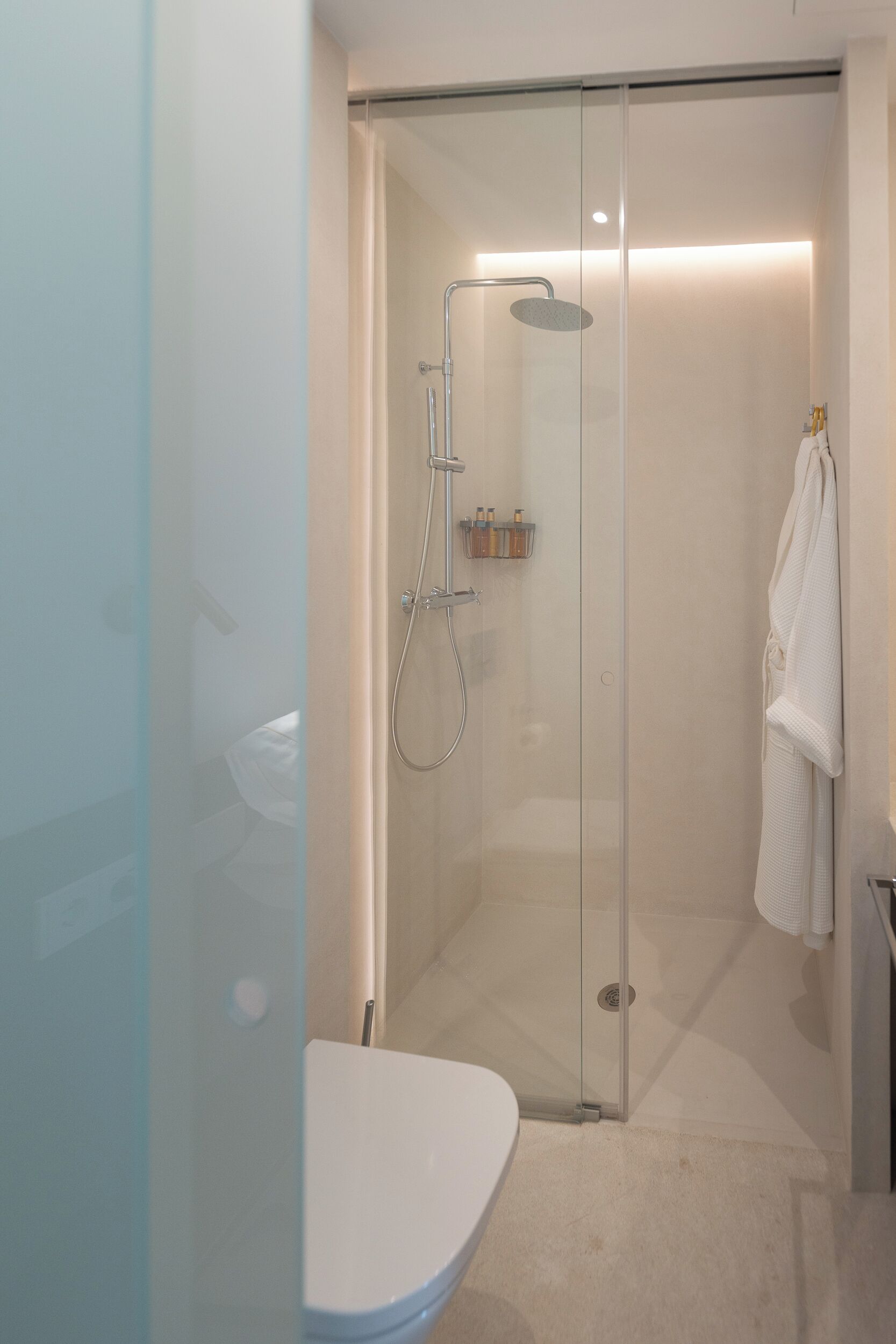 A modern bathroom with a glass-enclosed shower, a white toilet, and a towel hanging on the wall.