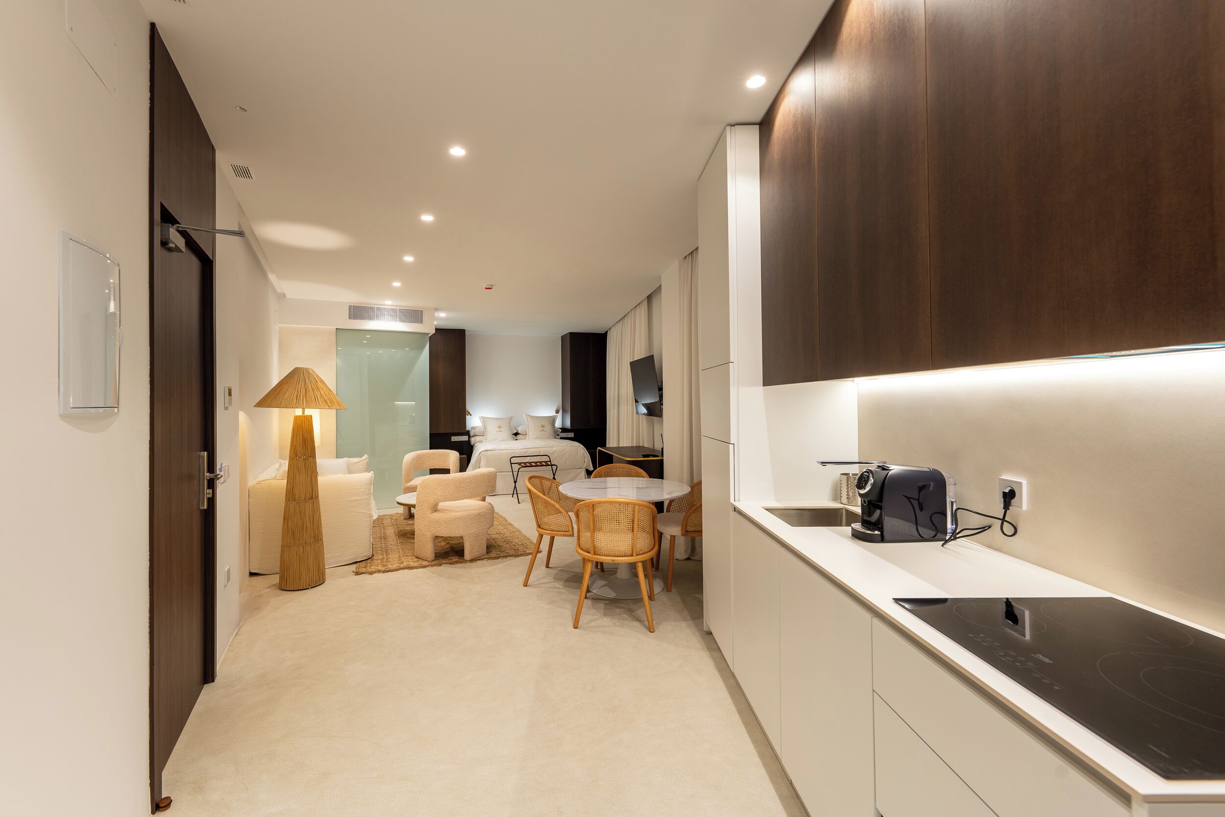 A modern kitchen with a built-in stove, a dining area with a round table and chairs, and a large window with a view of the city.