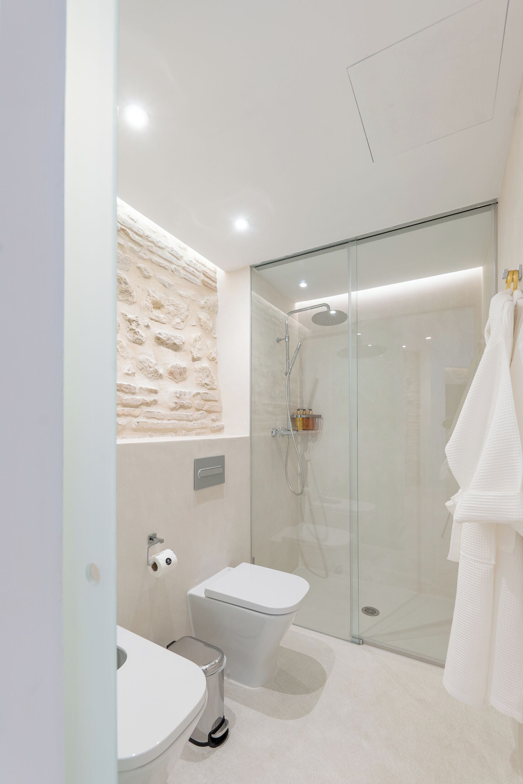 Een moderne badkamer met een douche met glazen wand, een toilet en een wastafel.