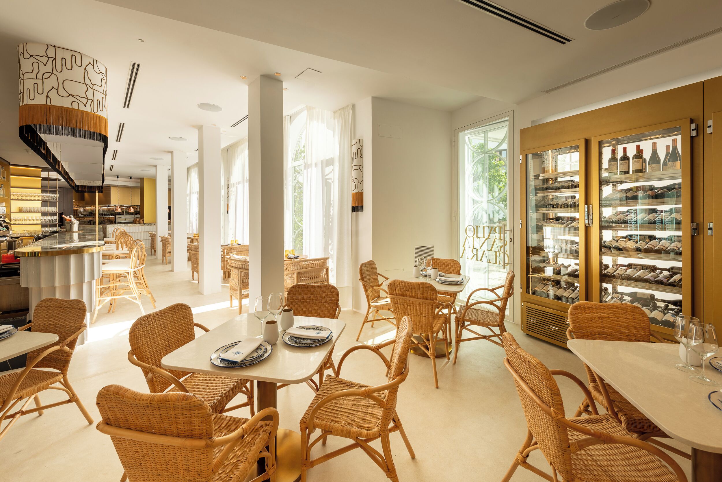 A spacious dining area with wicker furniture, a wine refrigerator, and a view of the outdoors.
