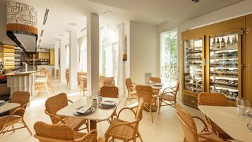 A spacious dining area with wicker furniture, a wine refrigerator, and a view of the outdoors.