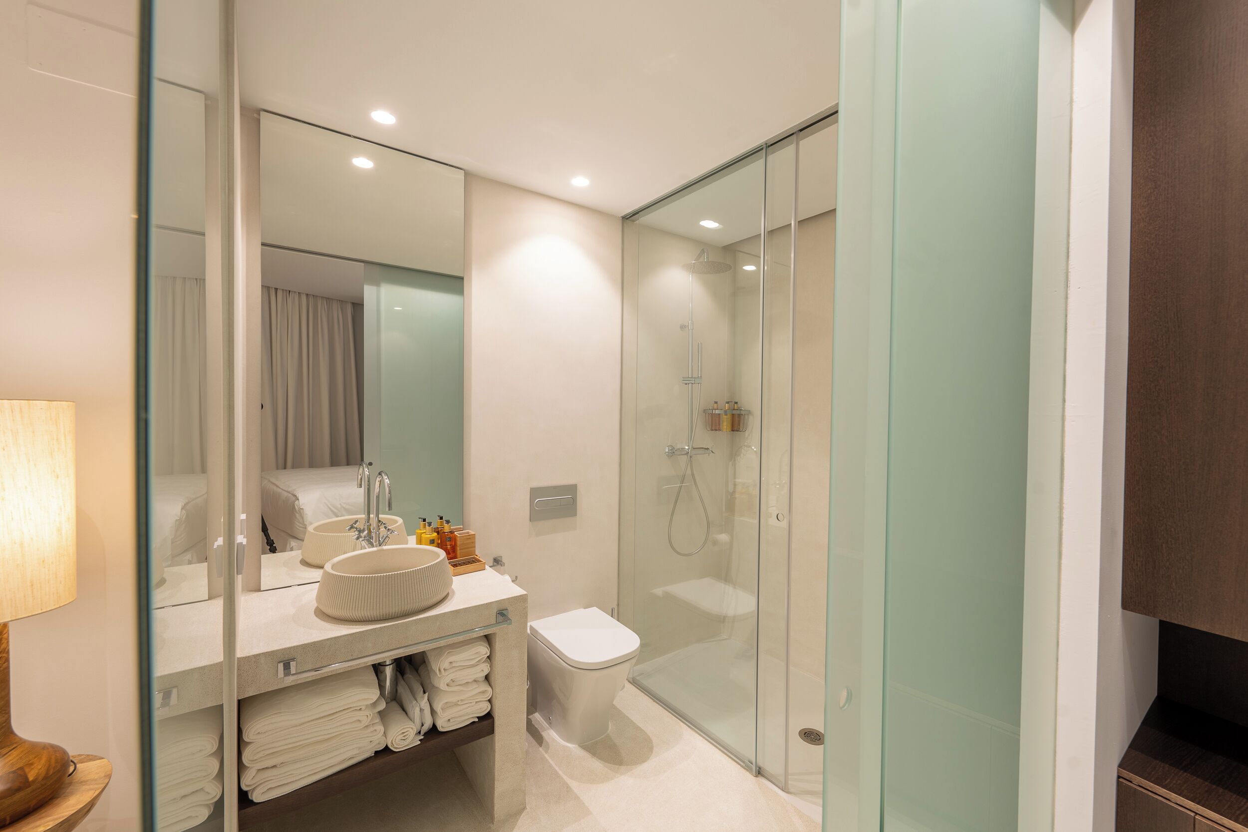 A modern bathroom with a glass-enclosed shower, a white sink, and a toilet.