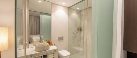 A modern bathroom with a glass-enclosed shower, a white sink, and a toilet.