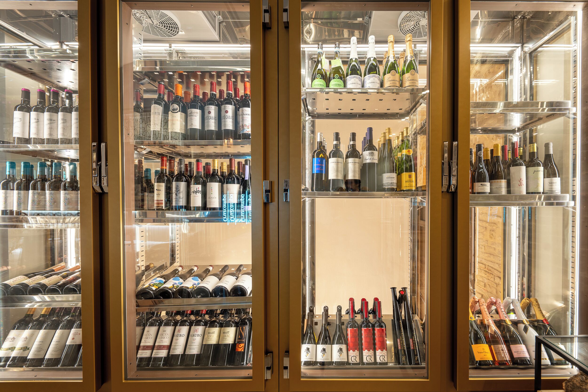 A wine refrigerator stocked with various bottles of wine.