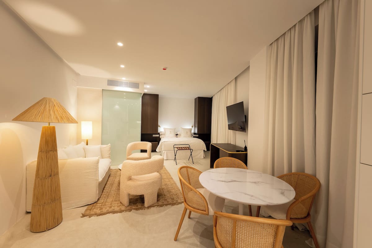 Une chambre d’hôtel comprenant un lit, un bureau, une télévision, une table à manger avec des chaises et une lampe.