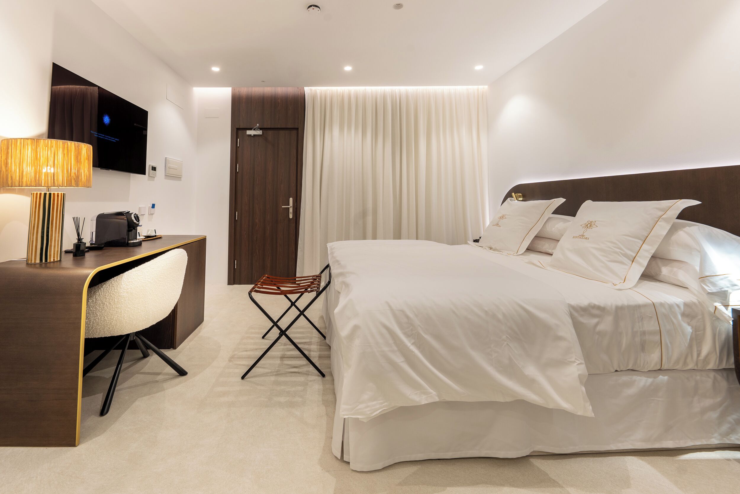 Una habitación de hotel con cama, escritorio, silla, televisor y puerta.