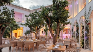 An outdoor dining area with wicker furniture and trees.