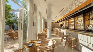 A spacious outdoor seating area with wicker furniture and a bar with neatly arranged bottles.