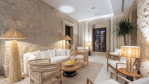 A modern living room with a stone wall, wicker furniture, and a large plant.