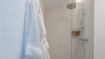 Un baño moderno con ducha de vidrio, inodoro y toallero con varias toallas.