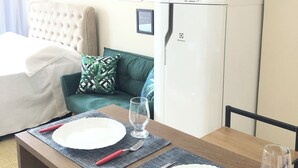 A neatly arranged dining area with a table set for two, a microwave, and a refrigerator in the background.