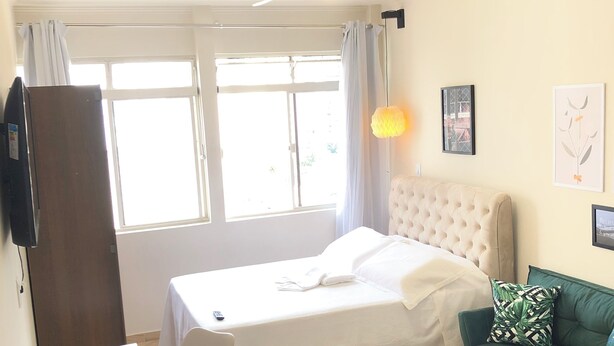A hotel room with a bed, a desk, a chair, a sofa, a table, and a ceiling fan.