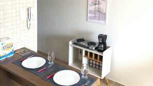 A compact kitchen with a dining area, a coffee maker, and a framed artwork on the wall.