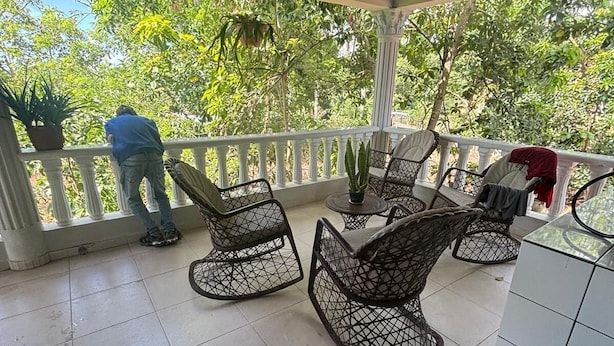 A covered outdoor area with tiled flooring, wicker furniture, and potted plants.