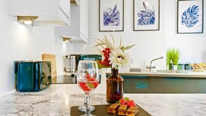 A marble countertop with a wine glass, a vase with flowers, and a tray of desserts. - Brighton Apartment Near Beach| Walk Everywhere (Brighton and Hove)