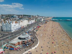 Un paysage urbain côtier avec une vaste plage, une promenade et un bâtiment remarquable surmonté d’un dôme.