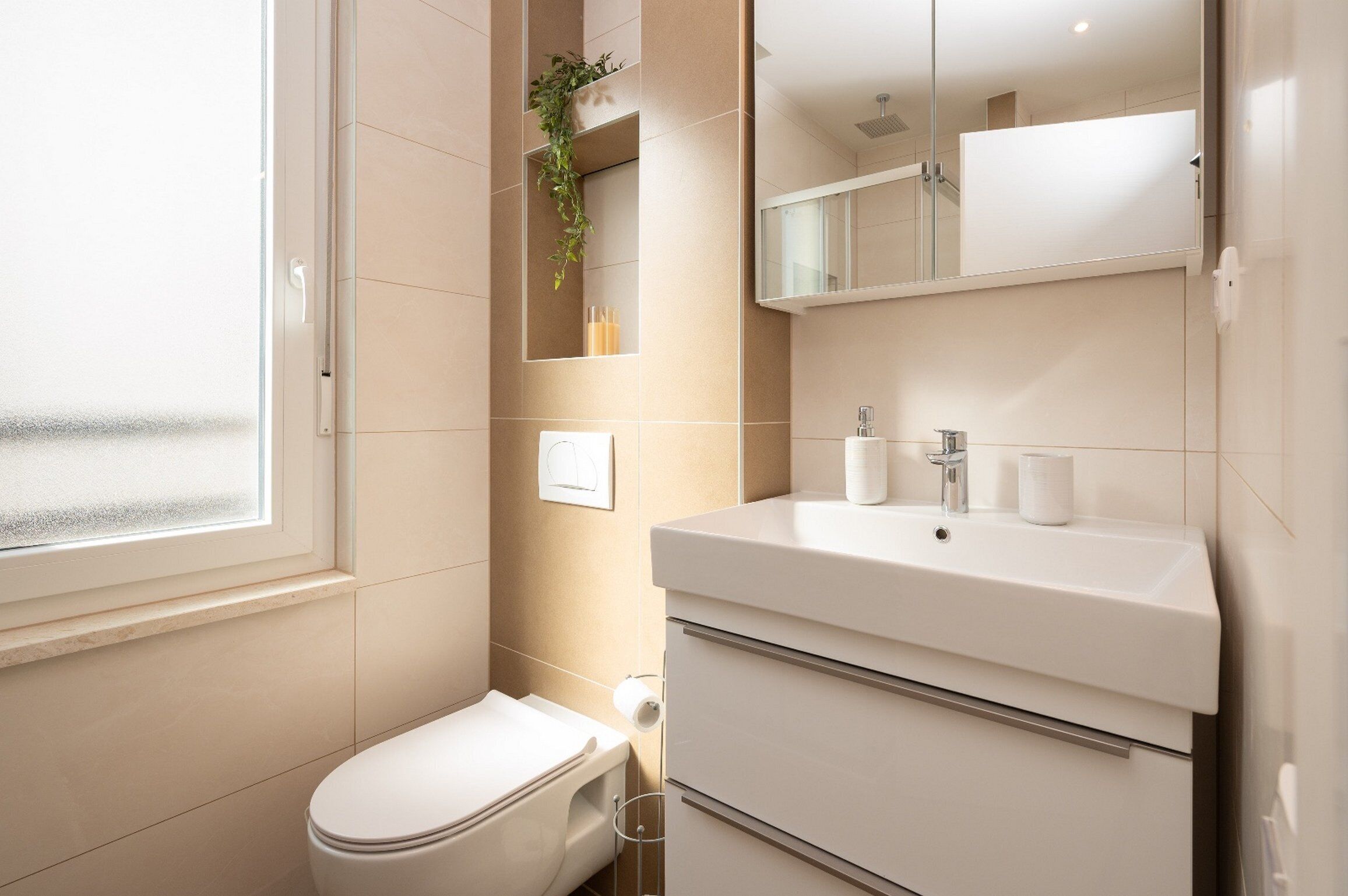 Un baño moderno con inodoro, lavabo y espejo.