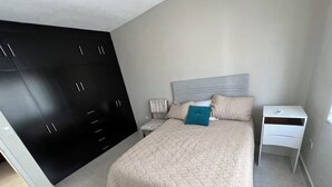 Une chambre à coucher comprenant un lit, une table de chevet, une armoire et une tête de lit.