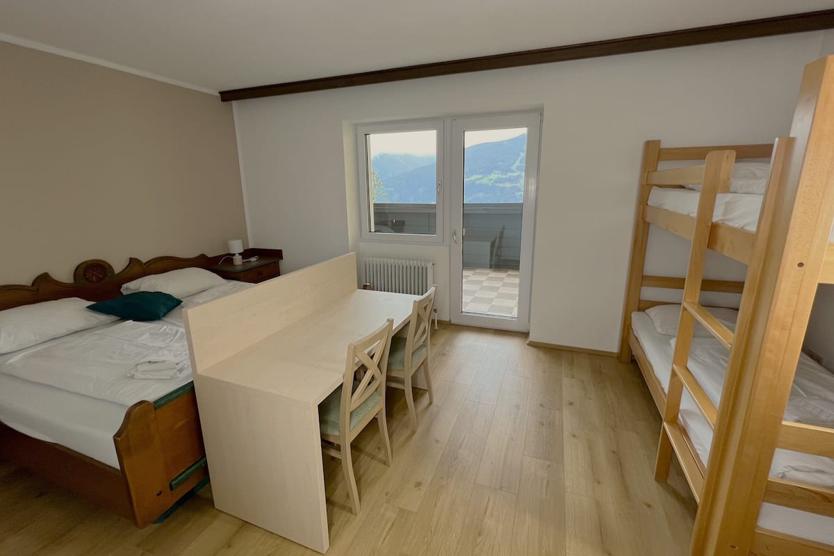 A bedroom with a bed, a desk, and a bunk bed.