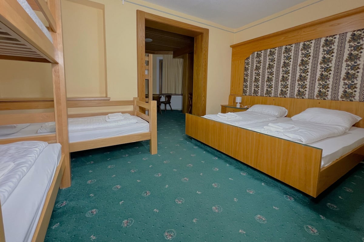 A room with bunk beds, a single bed, and a patterned carpet.