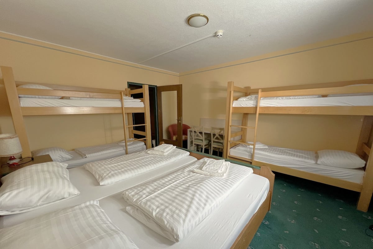 A room with bunk beds, a desk, and a chair.