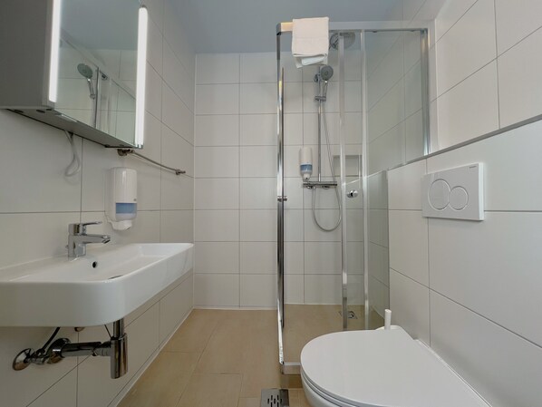 A modern bathroom with a white sink, mirror, and toilet. - Mountain Hostel (Ramsau am Dachstein)