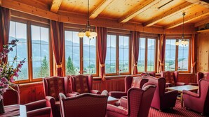A dining area with wooden ceiling and large windows offering mountain views. - Mountain Hostel (Ramsau am Dachstein)