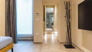 A hotel room with a bed, a large window with curtains, a hallway leading to a balcony, and a modern art piece. - Cozy studio apartment in the center of Bari, renovated and tastefully furnished (Bari)