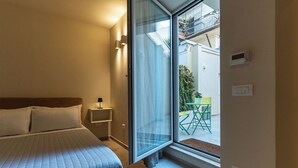 A bedroom with a bed, bedside table, and a window to a balcony. - Cozy studio apartment in the center of Bari, renovated and tastefully furnished (Bari)