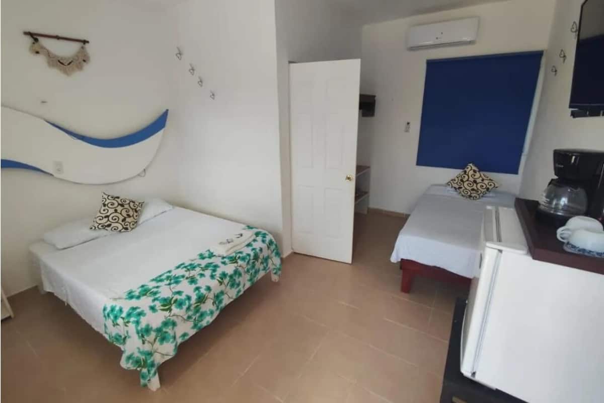 A room with two beds, a kitchenette, and a bathroom.