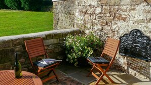Two wooden chairs with cushions, a bottle, and a magazine on a round table. - Buckstone House Coach House, Forest of Dean - sleeps 4 guests in 2 bedrooms (Forest of Dean)