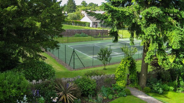A tennis court surrounded by lush greenery and a stone wall. - Buckstone House Coach House, Forest of Dean - sleeps 4 guests in 2 bedrooms (Forest of Dean)