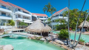 A resort with a pool, thatched-roof structures, and palm trees. - Noosa International 145 Noosa Heads (Noosa Heads)