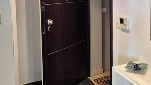 Un pasillo con una puerta de madera oscura, un aparador blanco y una alfombra estampada en el suelo.