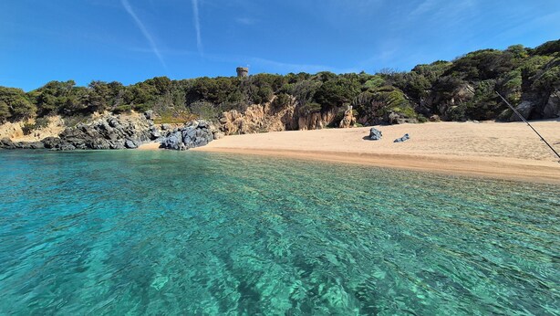 Una playa despejada con afloramientos rocosos y una orilla arenosa.
