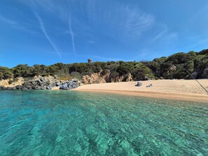 En lys strand med klipper og sand.