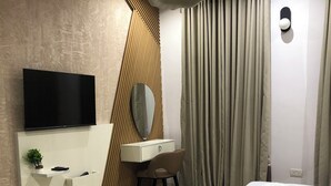 A modern bedroom with a flat-screen TV, a desk with a chair, a bed, and a large window with curtains. - Spacious 3-bedroom apartment with AC, WiFi in fabulous Ikeja (Ikeja)