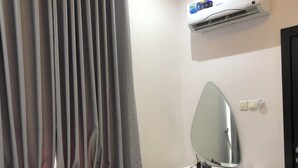 A hotel room with a bed, a desk with a chair, a mirror, and an air conditioning unit. - Spacious 3-bedroom apartment with AC, WiFi in fabulous Ikeja (Ikeja)