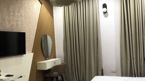 A modern hotel room with a large bed, a vanity with a mirror, a flat-screen TV, and a ceiling light fixture. - Spacious 3-bedroom apartment with AC, WiFi in fabulous Ikeja (Ikeja)