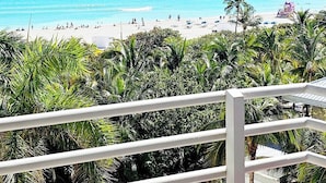 A beach view with clear turquoise water, palm trees, and a lifeguard tower. - Beach View at 101 Ocean Drive, SoFi in Miami Beach (Miami Beach)