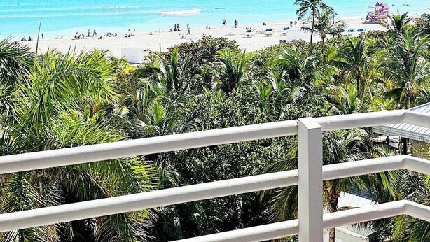 A beach view with clear turquoise water, palm trees, and a lifeguard tower.