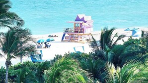 A beach with a sailboat named 'Caribbean Spirit' and a small beach hut with a purple roof.