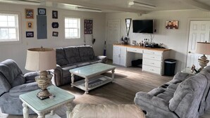 A spacious living room with a grey sofa, a coffee table, and a TV mounted on the wall. - Cozy 1-bedroom apartment in charming Burton 9 minutes from ROUND TOP! (Burton)