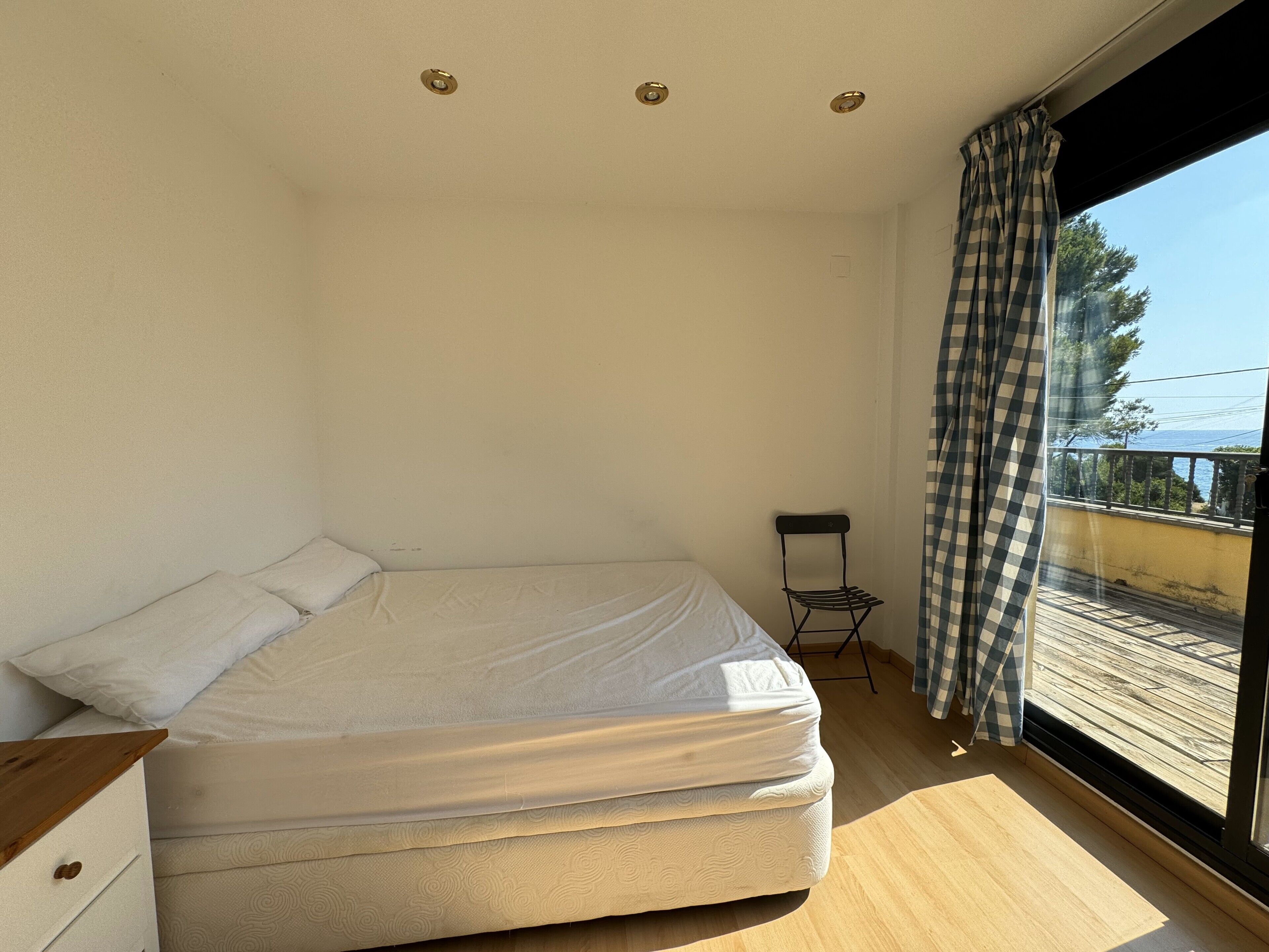 Ein Schlafzimmer mit Bett, Stuhl und einem Fenster mit Vorhängen.