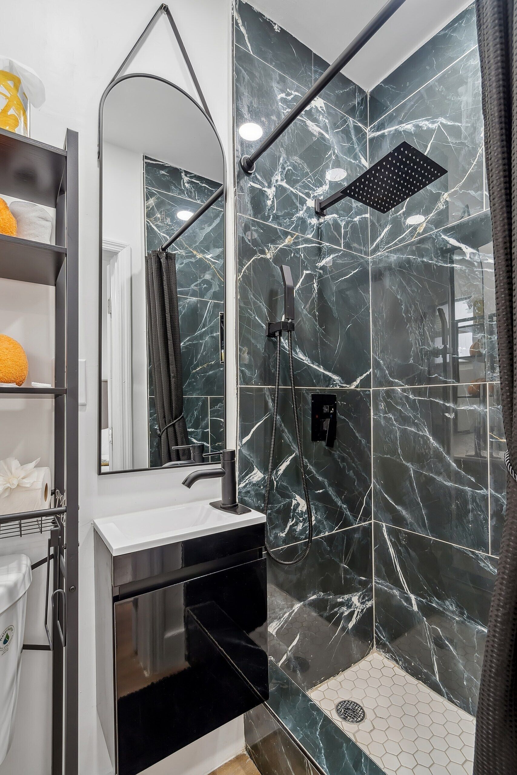 A modern bathroom with a glass-enclosed shower, a white sink, and a mirror above it.