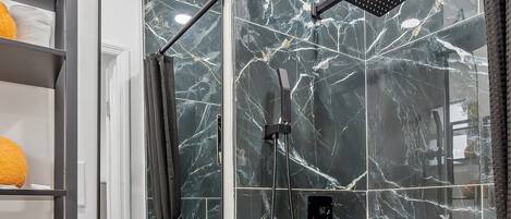 A modern bathroom with a glass-enclosed shower, a white sink, and a mirror above it.