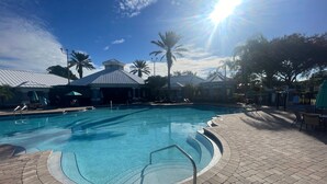 A swimming pool with a sunshade, lounge chairs, and a brick patio. - Beautiful Resort Near Theme Parks (Kissimmee)
